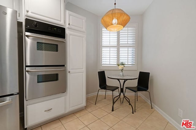 kitchen featuring stainless steel appliances, white cabinets, light tile patterned floors, and hanging light fixtures