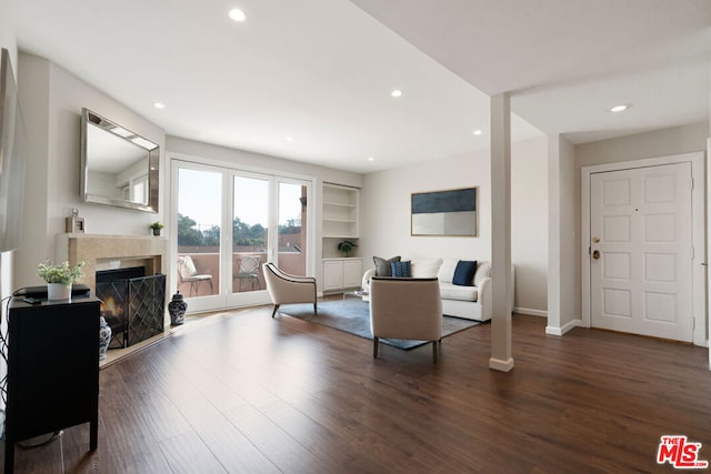 living room with built in shelves and dark wood-type flooring