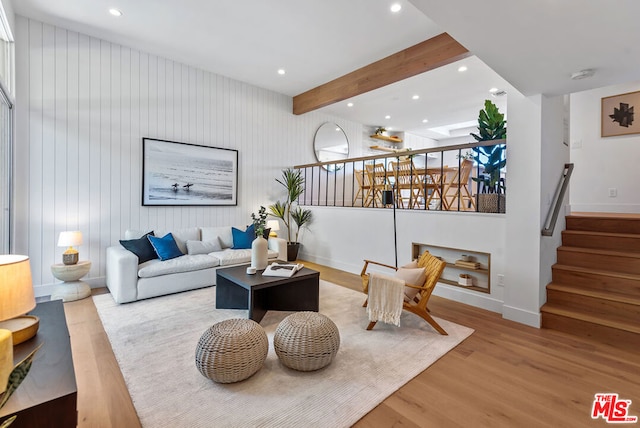 living room featuring light wood-type flooring, wooden walls, and beamed ceiling