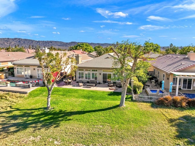 rear view of house with a patio, a lawn, and a mountain view