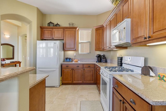 kitchen featuring white appliances, light stone countertops, and light tile patterned floors