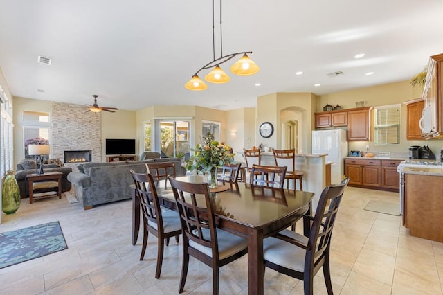 dining space with ceiling fan and a fireplace