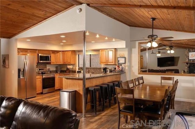 kitchen with wooden ceiling, a breakfast bar area, appliances with stainless steel finishes, kitchen peninsula, and backsplash