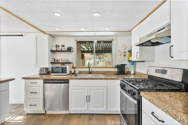 kitchen featuring white cabinets, stainless steel appliances, sink, stone countertops, and light hardwood / wood-style flooring