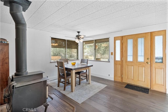 dining area featuring ceiling fan, dark hardwood / wood-style floors, and a wood stove