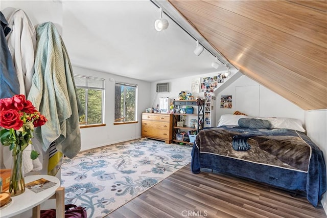 bedroom with hardwood / wood-style flooring, an AC wall unit, and track lighting