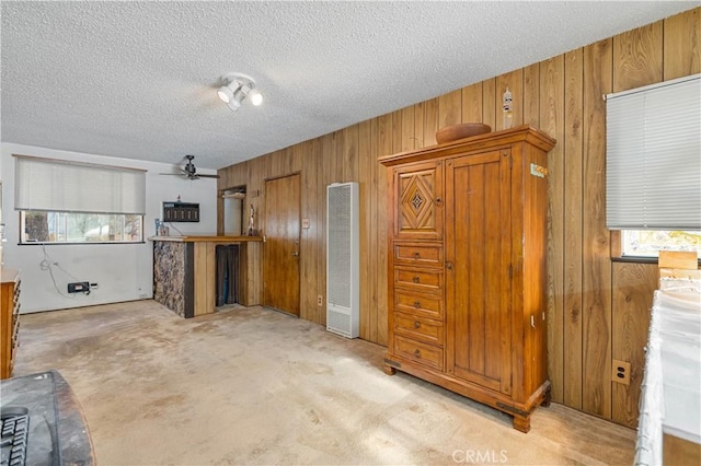 kitchen featuring ceiling fan, light carpet, wood walls, and a textured ceiling