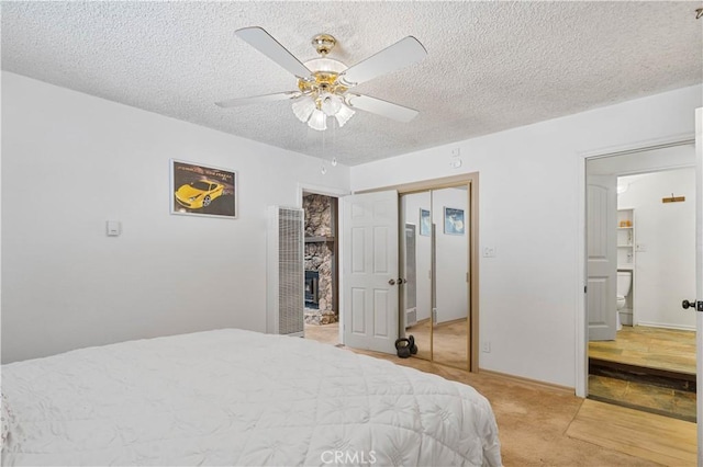 bedroom with a textured ceiling, ceiling fan, ensuite bathroom, and light colored carpet