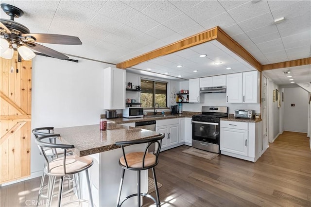 kitchen with kitchen peninsula, a breakfast bar area, stainless steel appliances, white cabinets, and sink