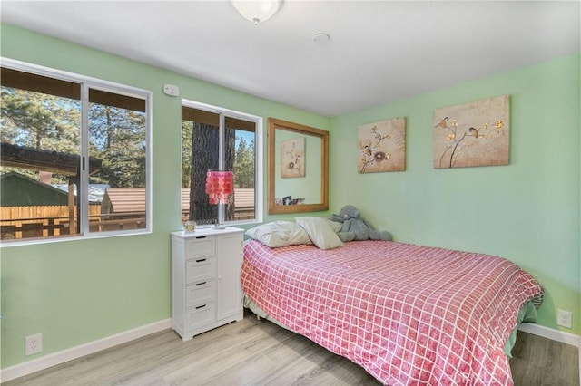 bedroom with light hardwood / wood-style floors and multiple windows