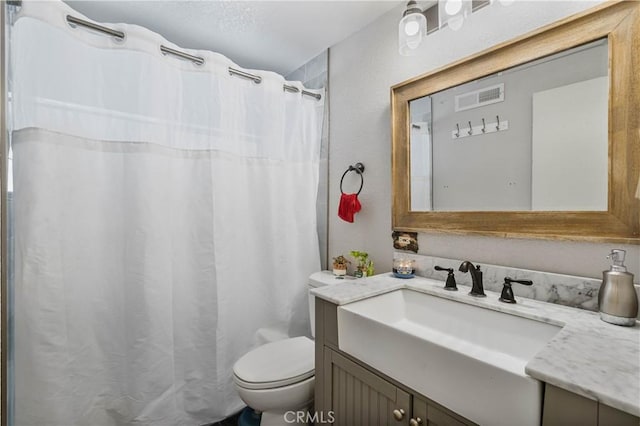 bathroom with toilet, vanity, and walk in shower