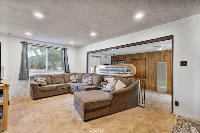 living room featuring light colored carpet, wood walls, and a textured ceiling