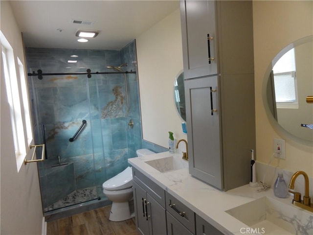 bathroom with hardwood / wood-style floors, an enclosed shower, vanity, and toilet