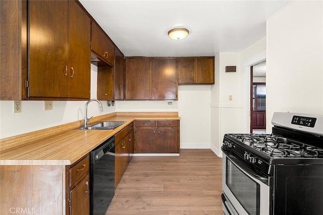 kitchen with gas range, sink, black dishwasher, and light hardwood / wood-style flooring