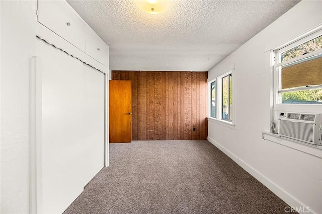 empty room featuring carpet, a textured ceiling, cooling unit, and wooden walls