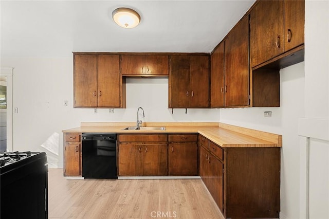 kitchen with black appliances, sink, and light hardwood / wood-style flooring