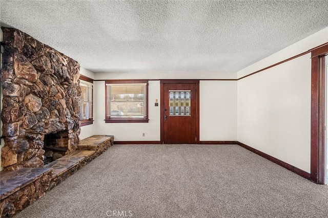 unfurnished living room featuring a textured ceiling, carpet floors, and a stone fireplace