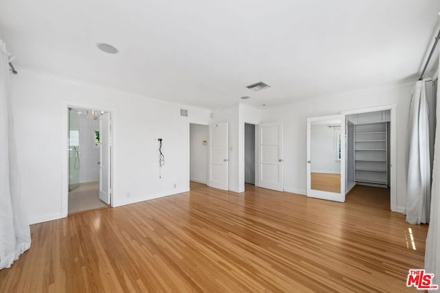 unfurnished bedroom featuring connected bathroom, an inviting chandelier, crown molding, and wood-type flooring