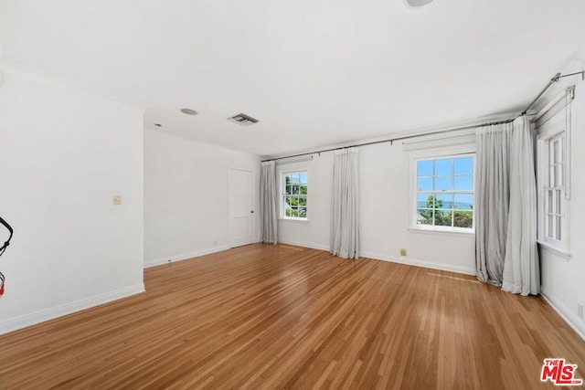 empty room with ornamental molding and light wood-type flooring