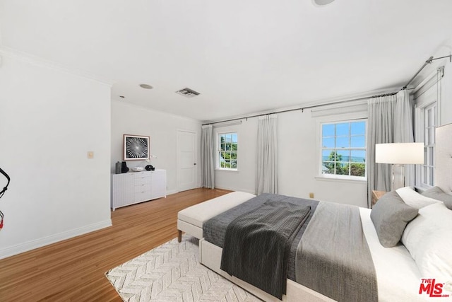 bedroom with light wood-type flooring and crown molding