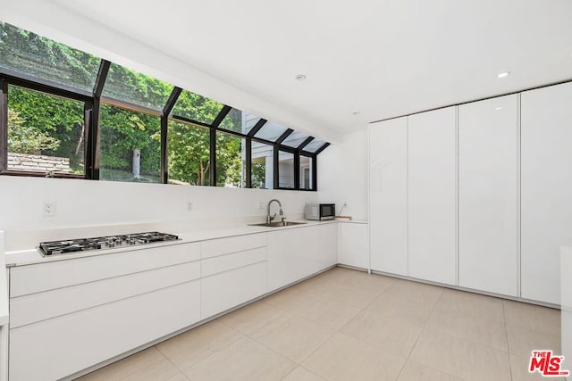 kitchen featuring stainless steel appliances, white cabinetry, a wealth of natural light, and sink