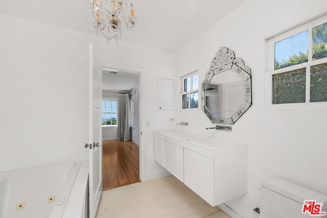 bathroom with toilet, a bath, a chandelier, and vanity