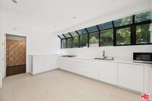 kitchen featuring sink, white cabinets, gas stovetop, and light tile patterned floors