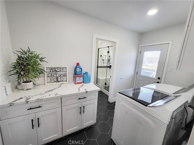 washroom featuring cabinets, washing machine and clothes dryer, and dark tile patterned floors