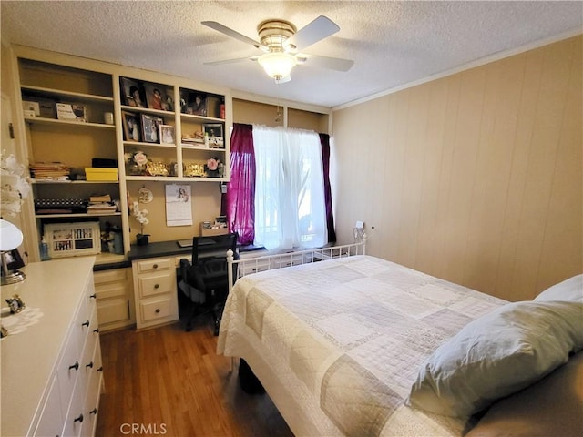 bedroom with wooden walls, a textured ceiling, ceiling fan, ornamental molding, and wood-type flooring