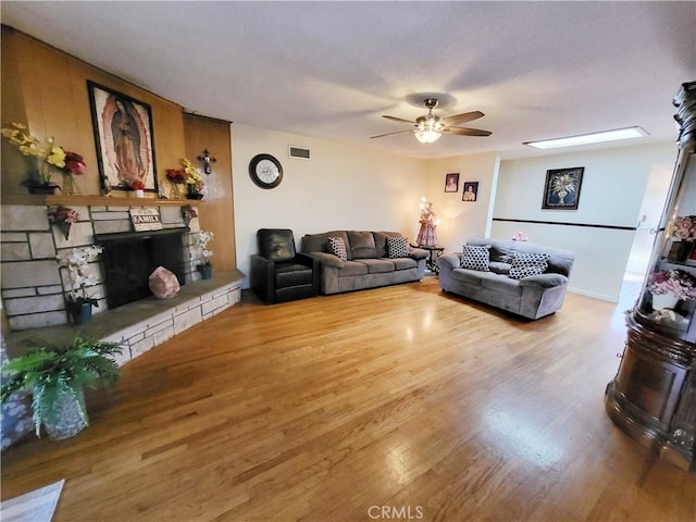 living room featuring a fireplace, ceiling fan, and wood-type flooring