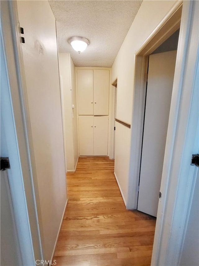 hallway featuring a textured ceiling and light hardwood / wood-style floors