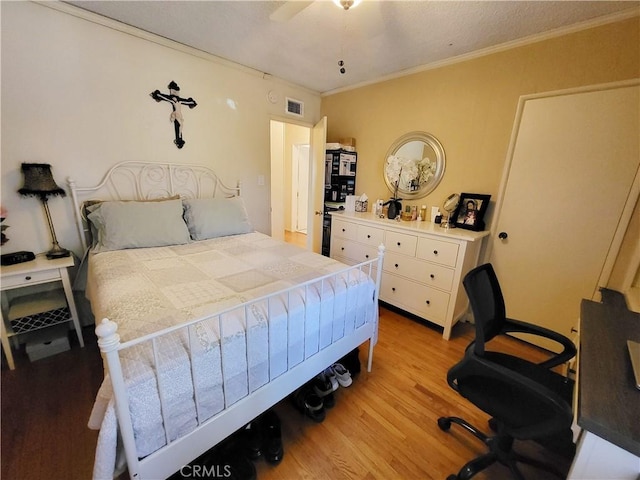 bedroom with ceiling fan, light hardwood / wood-style floors, and ornamental molding