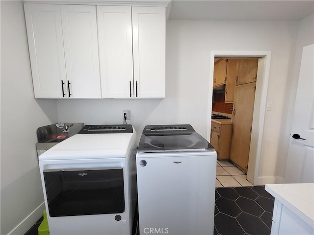 laundry room with dark tile patterned floors, cabinets, and washing machine and dryer