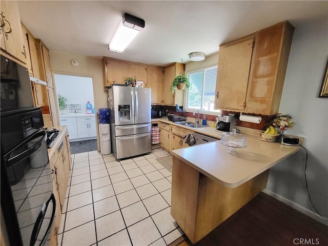 kitchen featuring kitchen peninsula, stainless steel appliances, light brown cabinetry, light tile patterned flooring, and sink