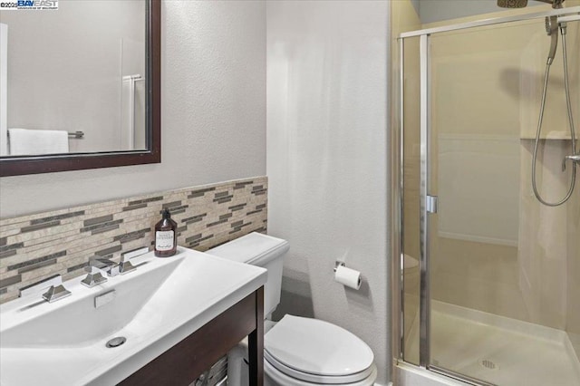 bathroom with tasteful backsplash, vanity, toilet, and a shower with door