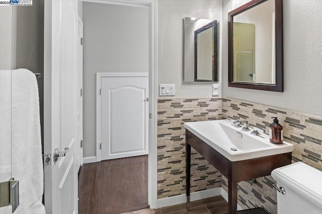 bathroom with tile walls, wood-type flooring, and toilet