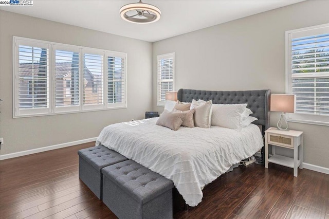 bedroom with dark hardwood / wood-style floors and multiple windows