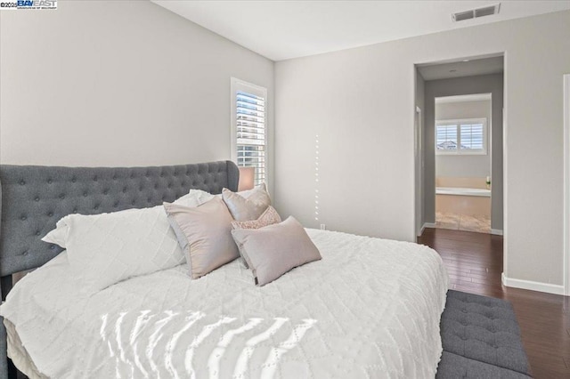 bedroom featuring multiple windows and dark hardwood / wood-style flooring