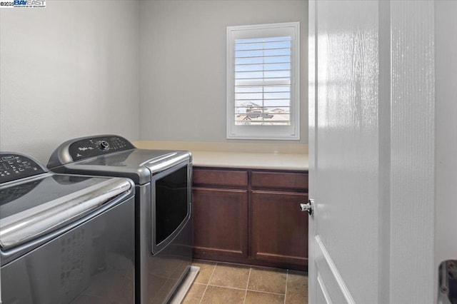 laundry area featuring light tile patterned floors, washer and clothes dryer, and cabinets