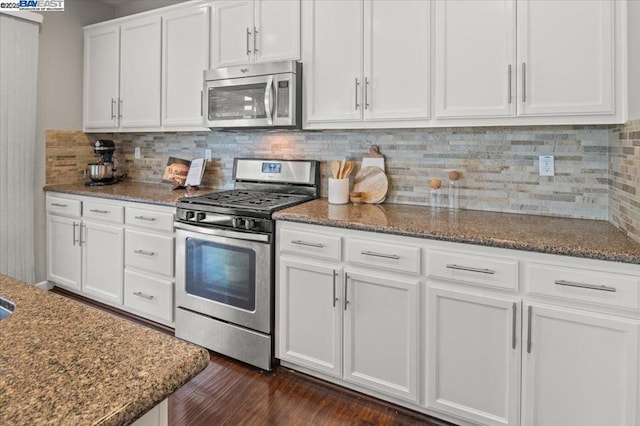 kitchen featuring dark stone countertops, appliances with stainless steel finishes, and white cabinets