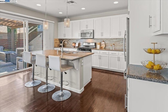 kitchen featuring white cabinetry, sink, dark hardwood / wood-style flooring, dark stone counters, and stainless steel appliances