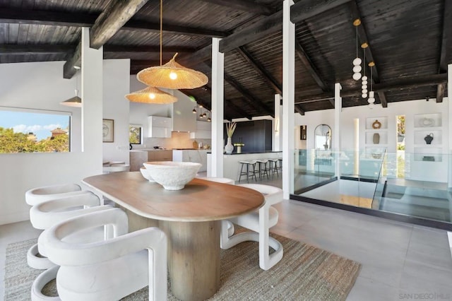 unfurnished dining area featuring high vaulted ceiling, beam ceiling, concrete floors, and wood ceiling