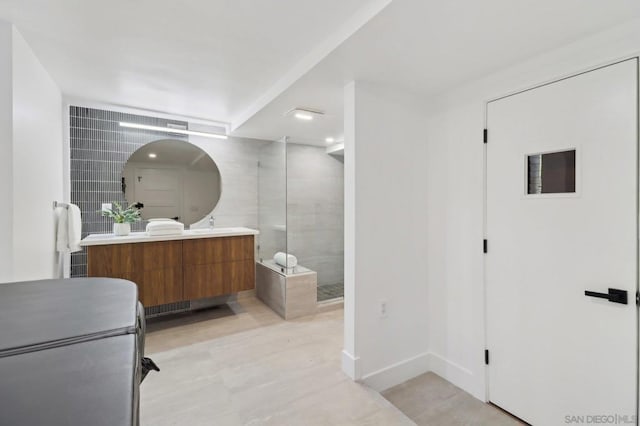 bathroom featuring a shower with shower door and vanity