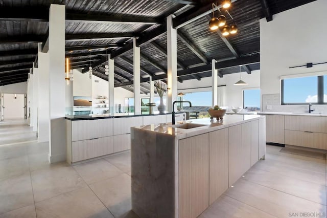 kitchen with sink, an island with sink, high vaulted ceiling, and beamed ceiling