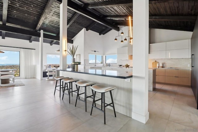 kitchen featuring high vaulted ceiling, white cabinetry, and beamed ceiling