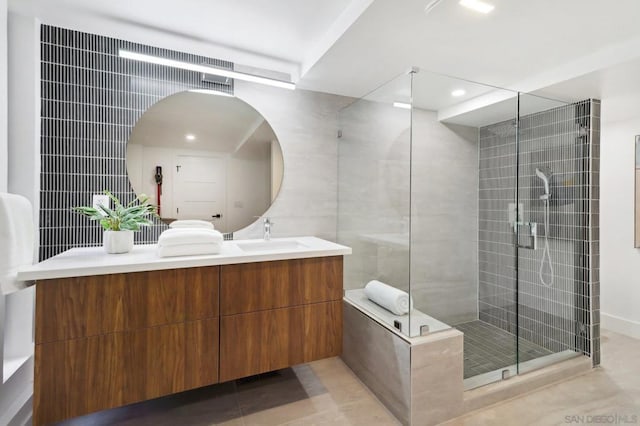 bathroom featuring tile walls, tile patterned floors, walk in shower, and vanity