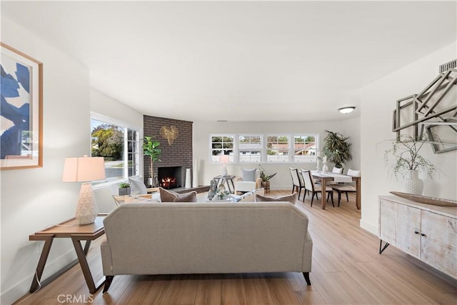 living room with a brick fireplace and light hardwood / wood-style floors