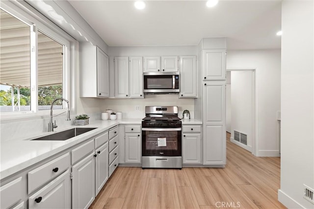 kitchen with sink, stainless steel appliances, light hardwood / wood-style flooring, and white cabinets