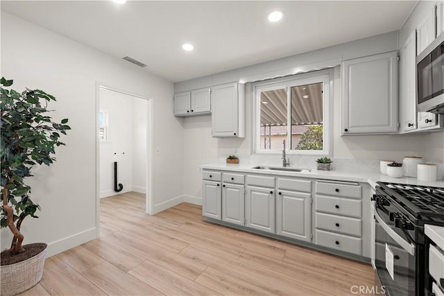 kitchen featuring black gas range oven, light hardwood / wood-style flooring, and sink