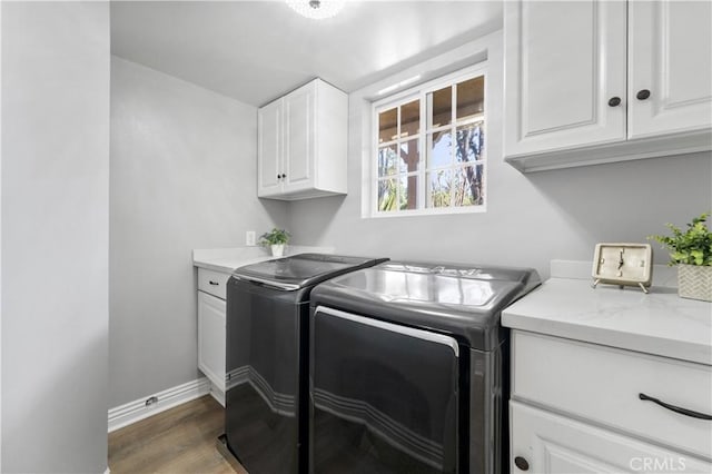 clothes washing area featuring washer and clothes dryer, wood finished floors, cabinet space, and baseboards